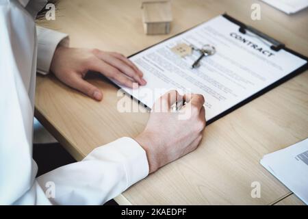 Der Kunde hält einen Stift in der Hand und liest den Kaufvertrag vor der Unterzeichnung. Stockfoto