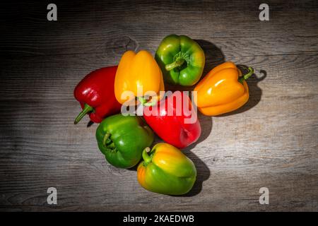Grüne rote und gelbe Paprika auf einer Holzoberfläche Stockfoto