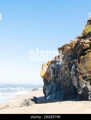 Eine vertikale Aufnahme von Meereswellen, die den felsigen Strand an einem sonnigen Tag waschen Stockfoto