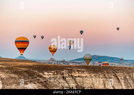 Eine Luftaufnahme von heißen Ballonen, die während des Sonnenuntergangs über Capadoccia am Himmel fliegen Stockfoto