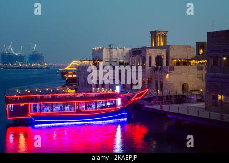 Dubai, VAE - 12.. oktober 2022: Beleuchtetes Vintage-Schiffrestaurant - Boot, das im Sommer an wunderschönen alten Gebäuden im alten Dubai Creek-Viertel angedockt ist Stockfoto