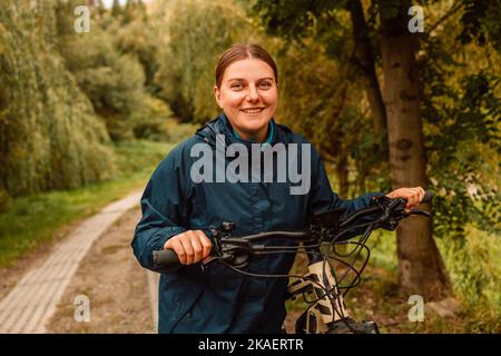 Junge aktive Mädchen in Sportbekleidung mit einem Fahrrad in einem Berggebiet, genießt Sommerurlaub Stockfoto