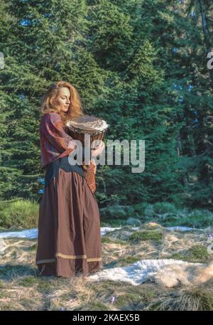 Schöne schamanische Mädchen spielt auf afrikanischen Trommel in der Natur. Stockfoto