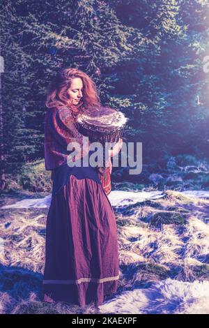 Schöne schamanische Mädchen spielt auf afrikanischen Trommel in der Natur. Stockfoto