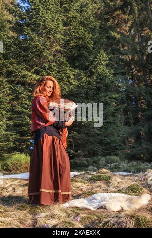 Schöne schamanische Mädchen spielt auf afrikanischen Trommel in der Natur. Stockfoto