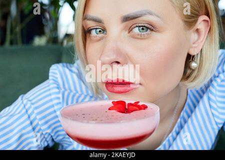 Porträt einer attraktiven jungen Frau, die im Café drinnen Koktopf trinkt Stockfoto