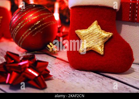 Weihnachtliche rote und goldene Hintergründe mit Kugeln, Schleifen, Weihnachtsstrumpfen und Geschenken. Stockfoto