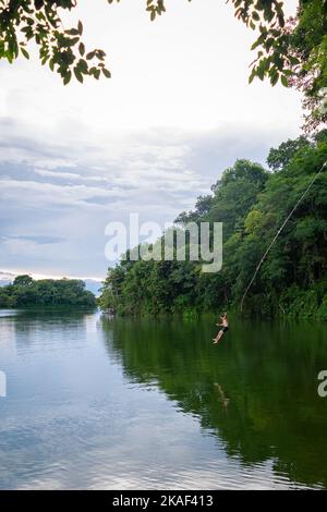 Eine vertikale Aufnahme eines Touristen, der von einer Seilschaukel am Peten Itza See in Flores, Guatemala, taucht Stockfoto