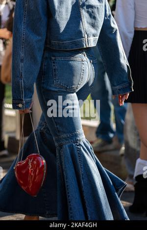 Mailand, Italien - 22. September 2022: Frau trägt Denim-Jacke, Crinoline Denim-ausgestellte Jeans, rote herzförmige Tasche von YSL Yves Saint Laurent, Street Stockfoto