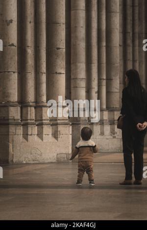 Der kleine Junge blickt voller Staunen auf die riesigen Steinsäulen im Kölner Dom Stockfoto