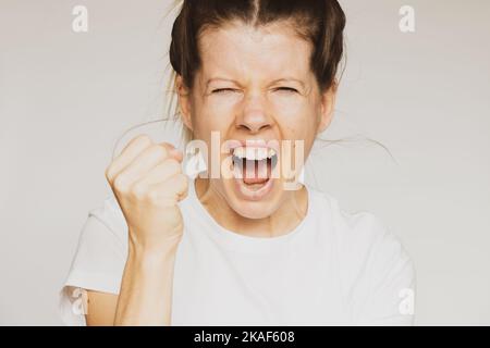 Mädchen schrie und winkte ihre Faust über isolierten Hintergrund Nahaufnahme, schlechten Tag und keine Stimmung Stockfoto