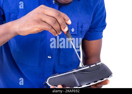 Die Hände eines männlichen Technikers, der sein Mobiltelefon mit einem Schraubendreher repariert. Stockfoto