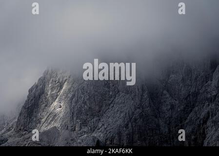 Eine rote Kabine der Lagazuoi-Seilbahn vor einer Felswand verschwindet in den Wolken über dem Falzarego-Pass, Dolomiten, Italien Stockfoto