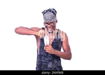 Ein gutaussehender, fröhlicher junger Mann mit Tanktop und Bandana auf dem Kopf, der beim Lächeln eine Flasche Mineralwasser öffnete. Stockfoto