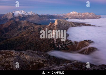 Kalter Nebel, der im Morgengrauen über den Valparola-Pass vor dem Settsass und dem Sella-Massiv, Dolomiten, Italien, strömt Stockfoto