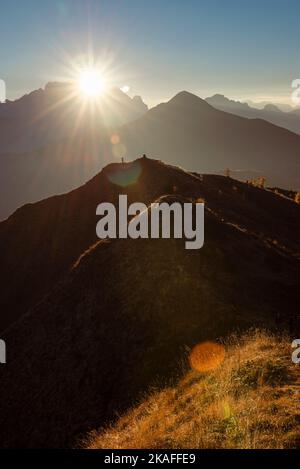 Wanderer auf einem Panorama-Gipfel am Passo di Giau im warmen Licht des Sonnenuntergangs über dem Gipfel der Marmolada, Dolomiten, Italien Stockfoto