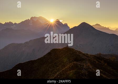 Wanderer auf einem Panorama-Gipfel am Passo di Giau im warmen Licht des Sonnenuntergangs über dem Gipfel der Marmolada, Dolomiten, Italien Stockfoto