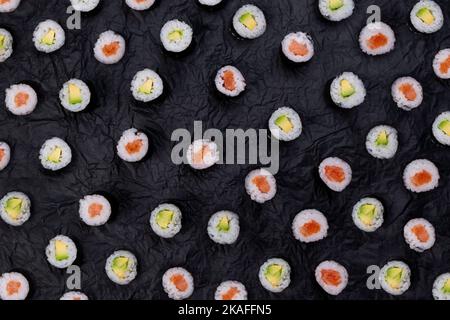 Sushi Maki Rollen auf schwarzem Hintergrund Draufsicht, Mode Food Hintergrund. Stockfoto