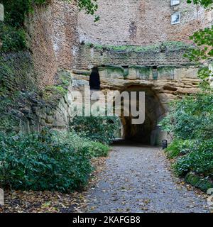 Unterer Eingang zum Park Tunnel, der einen Teil der steinernen Mauer und ungefüttertem Sandstein zeigt Stockfoto