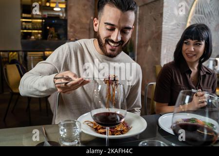 Glückliches Paar im Restaurant, das Nudeln im asiatischen Fusion Food Restaurant mit Essstäbchen, Menschen, Essen und Trinken Lifestyle-Konzept isst Stockfoto