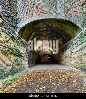 Upper Park Tunnel mit gemauertem Gewölbe und teils mit Stein ausgekleideten Wänden, teils mit ungefüttertem Fels, vom mittleren Schacht aus gesehen in Richtung eines teilweise geschlossenen oberen Ausgangs Stockfoto