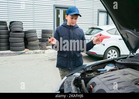 Ein Kindermechaniker wechselt die Sicherungen in einem Auto. Reparaturdienste im Autoservice. Auto-Reparatur-Konzept Stockfoto