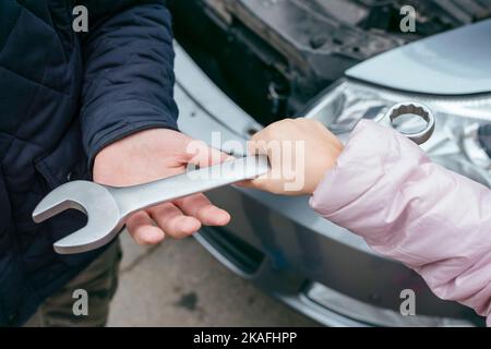 Nahaufnahme von zwei Mechanikern, die sich den Metallschlüssel teilen Stockfoto