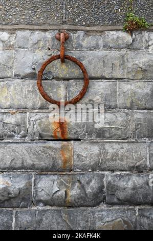 Alter rostiger Metallfestungsring an einer alten Wand. Rostige Kette aus Metall auf Steinmauer. Stockfoto