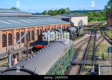 Personenwagen und alte Dampflokomotiven parkten an der Sheffield Park Station auf der historischen Bluebell Railway-Linie in East Sussex, England. Stockfoto