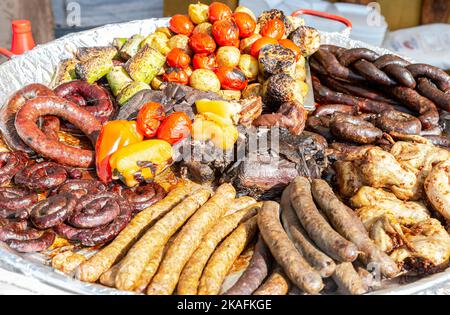 Appetitlich gebackenes Fleisch, Grillwurst und Gemüse in einer großen Bratpfanne Stockfoto