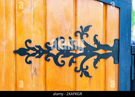 Türscharnier aus schwarzem Metall, an ein Holztor geschraubt Stockfoto