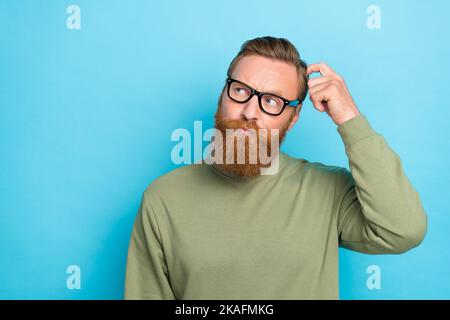 Foto-Porträt von attraktiven jungen Mann kratzen Kopf suchen leeren Raum gekleidet stilvolle khaki Outfit isoliert auf aquamarinfarbenem Hintergrund Stockfoto