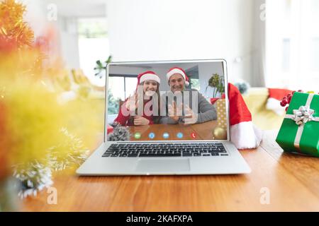 Ein erfahrener weißer Mann und seine Erwachsene Tochter, die ein weihnachtliches Videogespräch auf dem Laptop-Bildschirm führen Stockfoto
