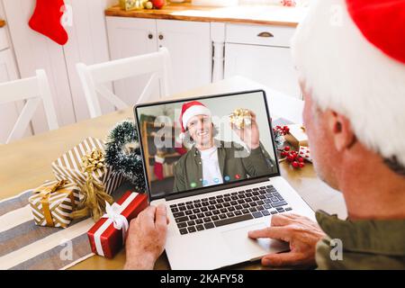 Ein weißer Mann mit weihnachtsmannmütze, der Videoanruf mit einem glücklichen Kaukasier führt Stockfoto