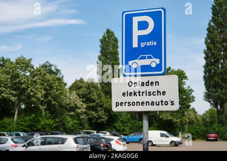 Parkplatz in den Niederlanden mit blauem kostenlosen Parkschild und Text zum Laden von elektrischen Personenkraftwagen in der niederländischen Sprache. Stockfoto