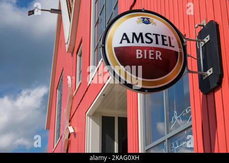 Amstel-Schild an einer roten Fassade im Sommer tagsüber. Amstel ist eine Biermarke des niederländischen Brauunternehmens Heineken. Es wurde 1870 in Amsterdam gegründet Stockfoto