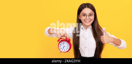 Guten Morgen. Pünktlichkeit. Letzte Chance. Daumen hoch. Pünktlich teen Mädchen Überprüfung Zeit. Teenager-Kind mit Wecker, horizontales Poster. Banner-Kopfzeile Stockfoto