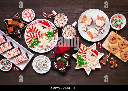 Süße Weihnachtsbonbons und Plätzchen-Tischszene. Blick von oben auf einem rustikalen dunklen Holzhintergrund. Fun Urlaub Backkonzept. Stockfoto