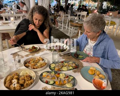 Malia, Kreta, Griechenland. 2022. Zwei Frauen in einem griechischen Restaurant genießen eine Auswahl kretischer Dushes. Stockfoto