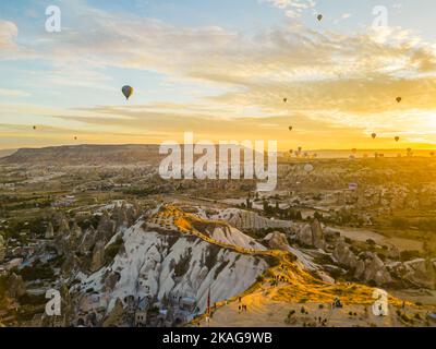Atemberaubende Drohnenansicht von Heißluftballons, die im Morgengrauen über das Rote Tal in Kappadokien in der Türkei fliegen. Feenkamine oder Hoodoos während des Sonnenaufgangs. Hochwertige Fotos Stockfoto