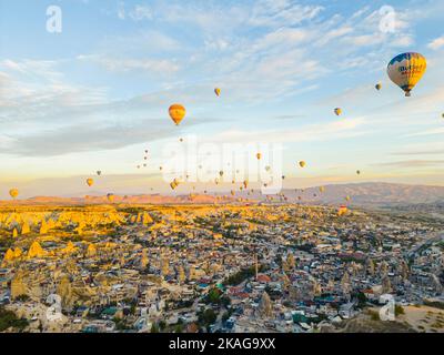 Atemberaubende Drohnenansicht von Hunderten von Heißluftballons, die während des Sonnenaufgangs über die ikonische Kappadokien der Türkei fahren, die Stadt inmitten des Tals der Feenkamine. Hochwertige Fotos Stockfoto