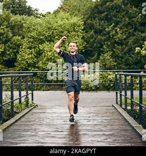 Jetzt hält mich nichts mehr auf. Porträt eines sportlichen jungen Mannes, der beim Training im Freien jubelt. Stockfoto