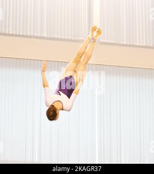 Mädchen trainieren im Trampolin und springen in einem stationären Raum Stockfoto