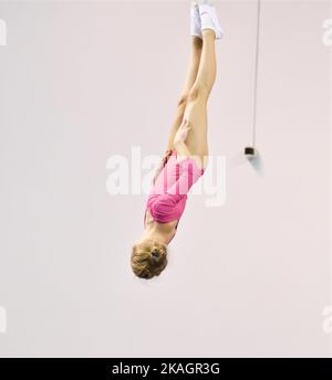 Mädchen trainieren im Trampolin und springen in einem stationären Raum Stockfoto