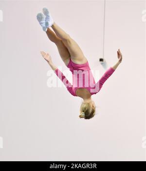 Mädchen trainieren im Trampolin und springen in einem stationären Raum Stockfoto