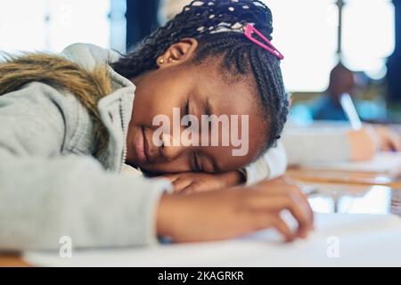 Ihr kleines Gehirn kann nur so viel tragen. Ein Mädchen aus der Grundschule schläft in der Klasse auf ihrem Schreibtisch. Stockfoto