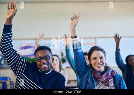 Wir alle wollen mehr im Leben. Eine Gruppe von Studenten, die ihre Hände in der Klasse heben. Stockfoto
