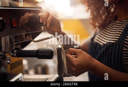 Heiß und frisch serviert. Nahaufnahme eines Barista, der eine Kaffeemaschine in einem Café betreibt. Stockfoto