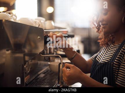 Sie weiß, wie man die perfekte Mischung zubereitet. Nahaufnahme eines Barista, der eine Kaffeemaschine in einem Café betreibt. Stockfoto