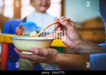 Es ist die Zeit des Tages, um Ihren Bauch zu füttern. Ein unkenntlich alleinerziehender Vater füttert sein Baby zu Hause. Stockfoto